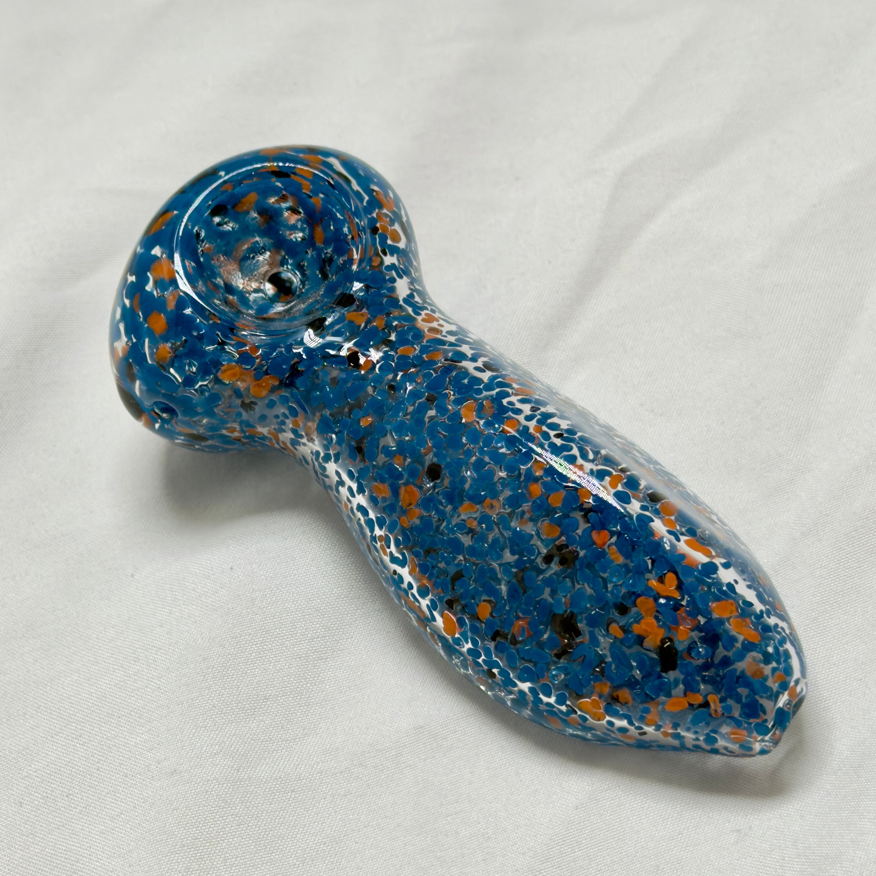 Blue and orange speckled glass pipe on a white background