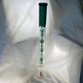 Glass water pipe with green top on a white fabric background