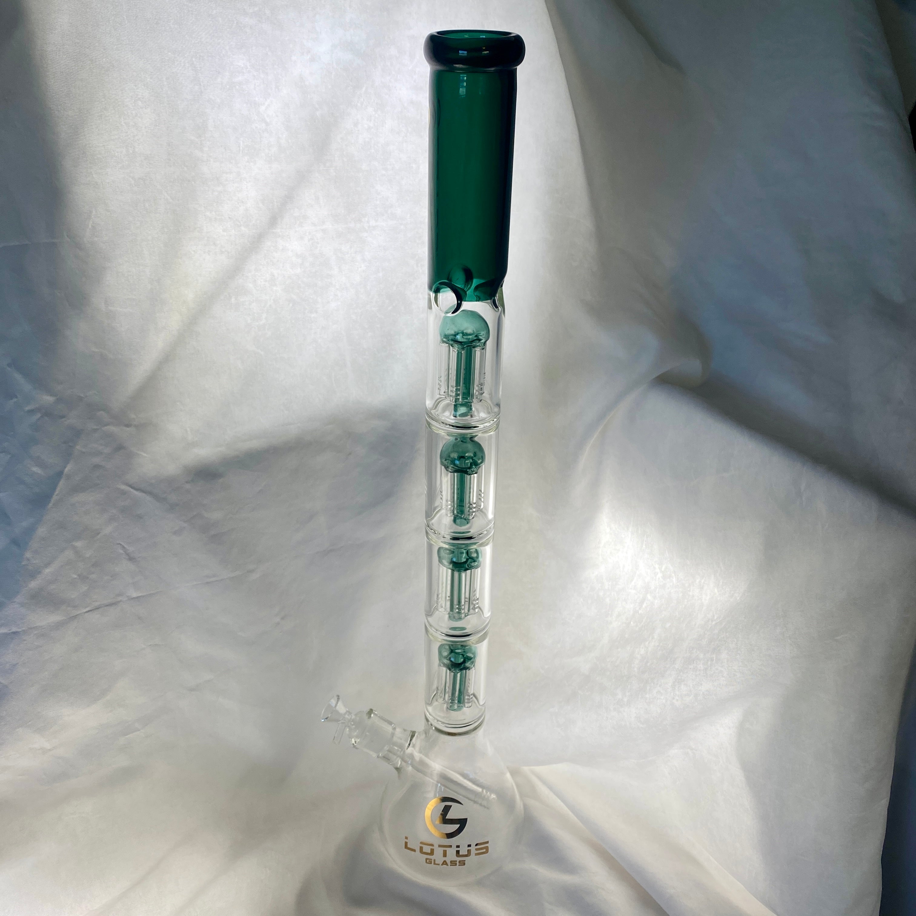 Glass water pipe with green top on a white fabric background