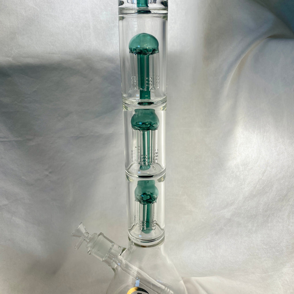 Glass water pipe with green accents on a white fabric background