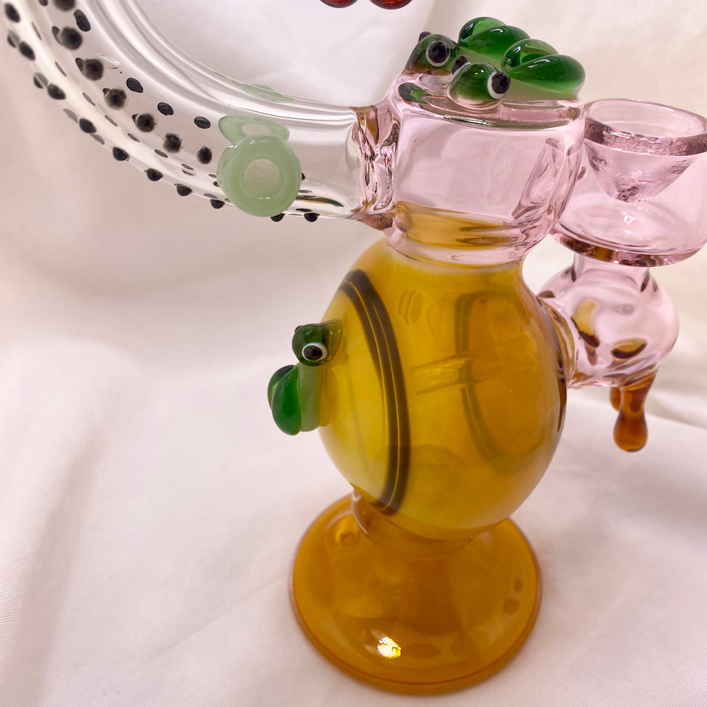 Glass smoking accessory shaped like a fish with green eyes on a white background