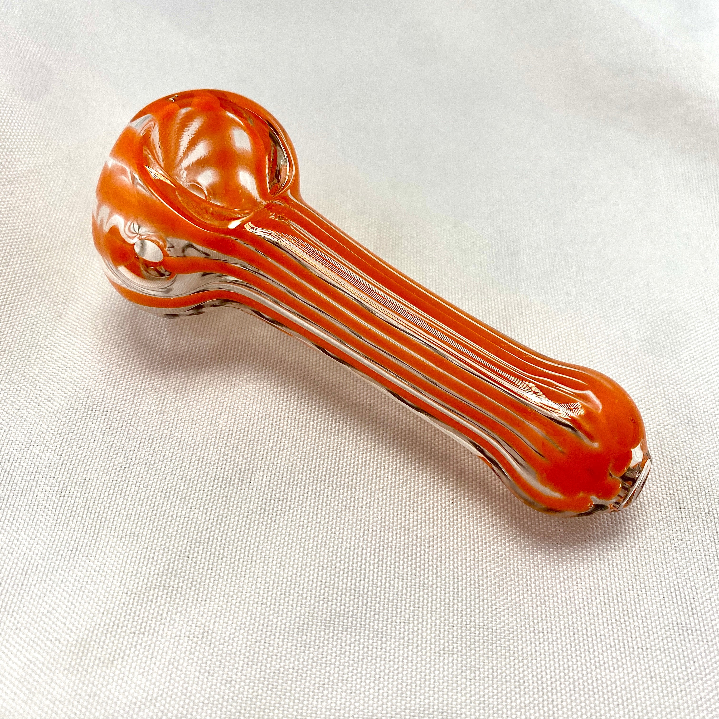 Glass smoking pipe with orange and clear design on a white background