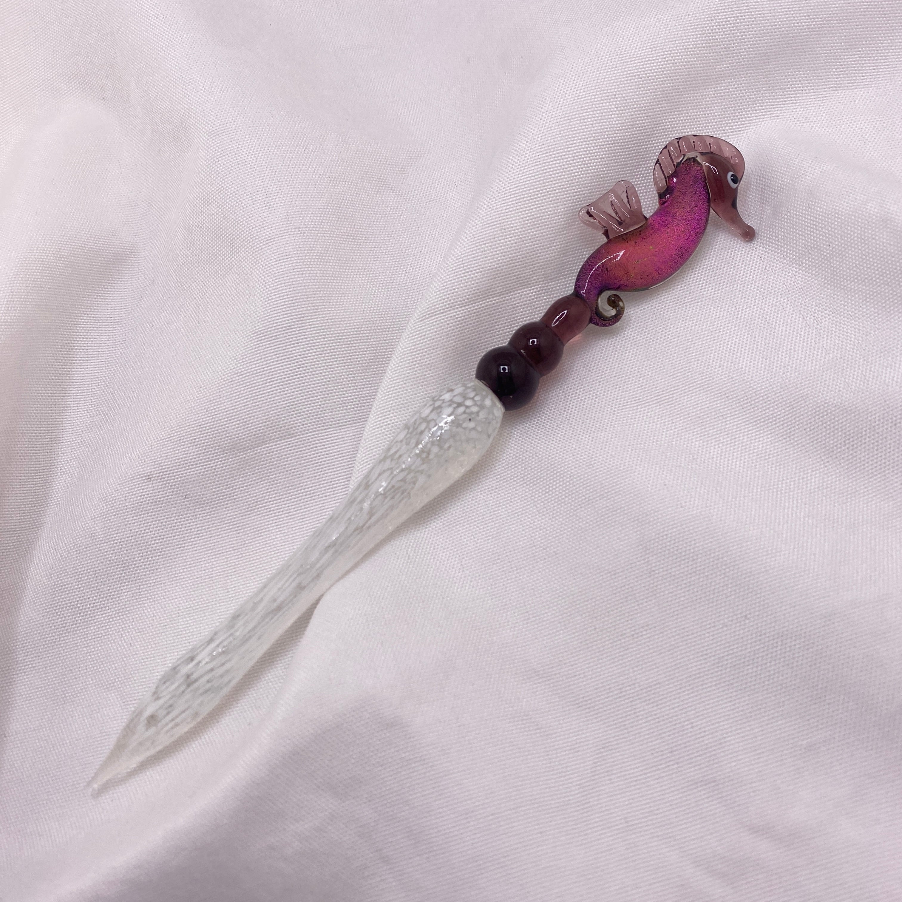 Decorative knife with a purple handle on a white fabric background