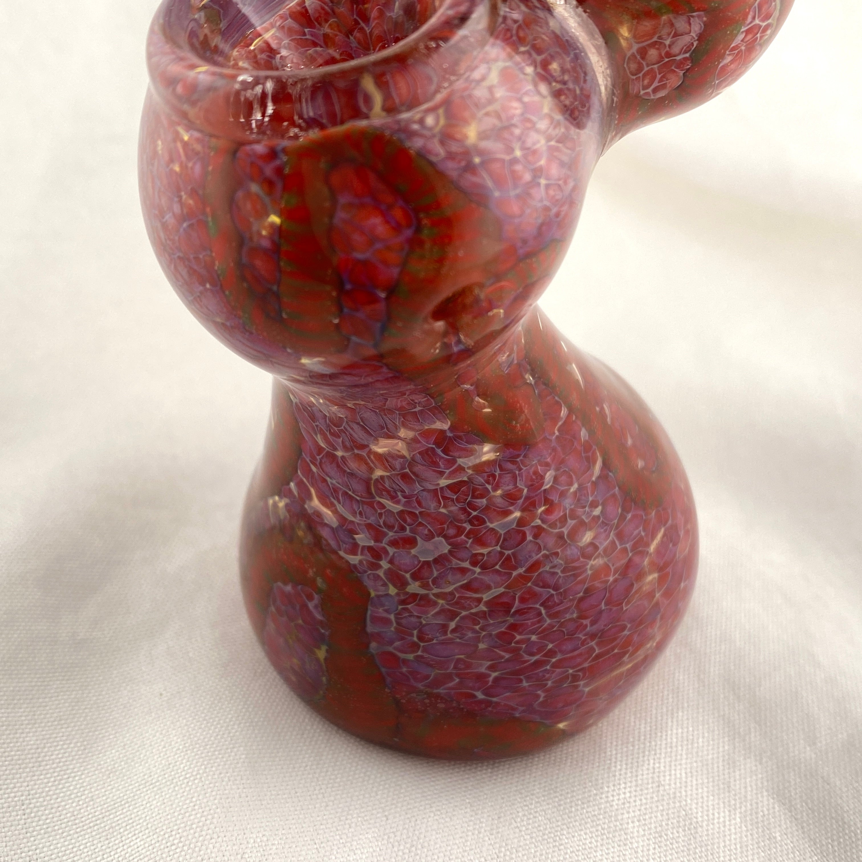 Decorative glass vase with marbled red and brown pattern on a white background