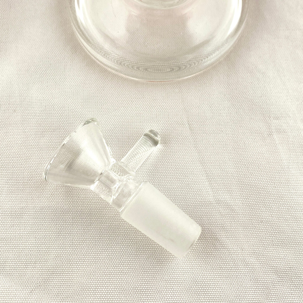 Clear glass smoking accessory on a light fabric background