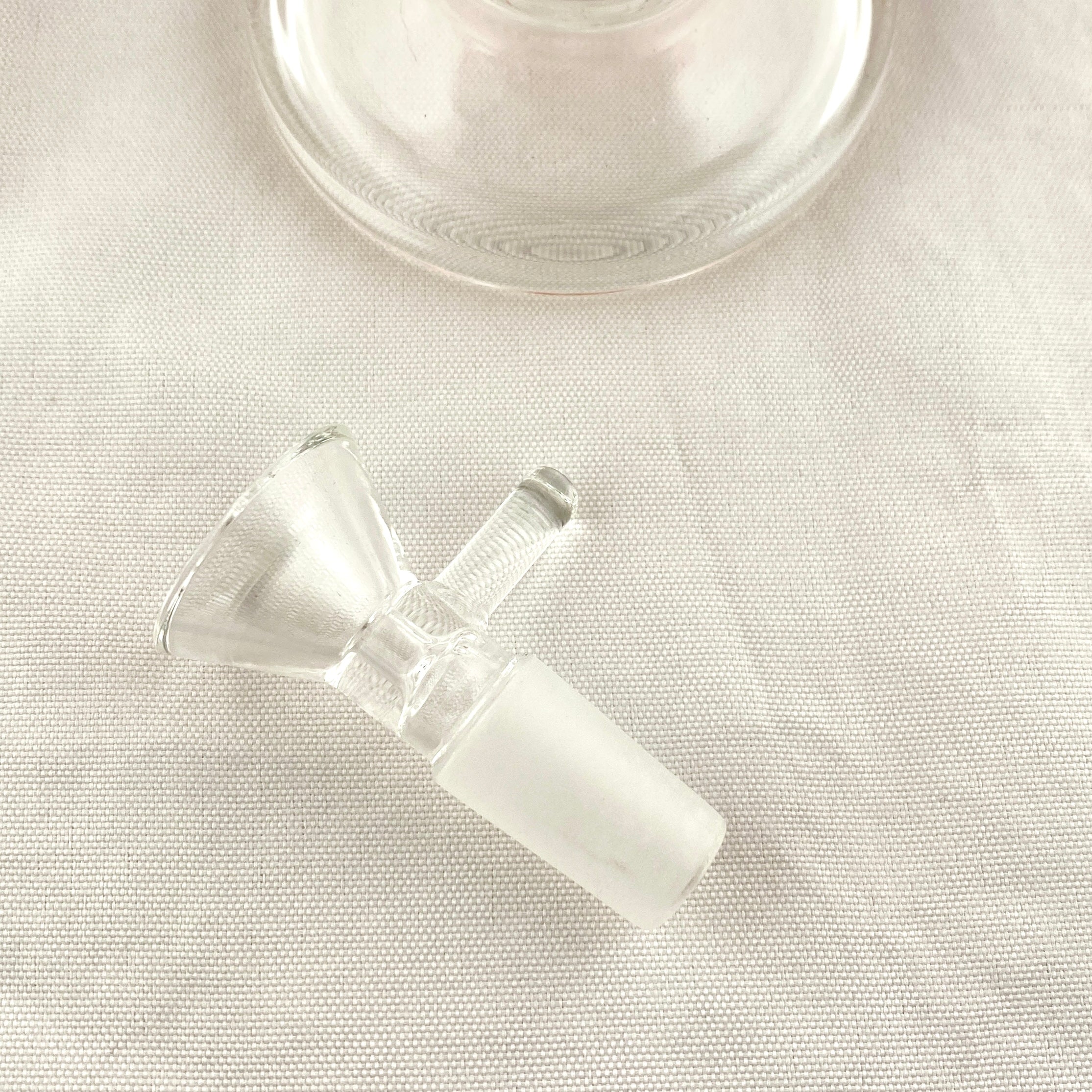 Clear glass smoking accessory on a light fabric background