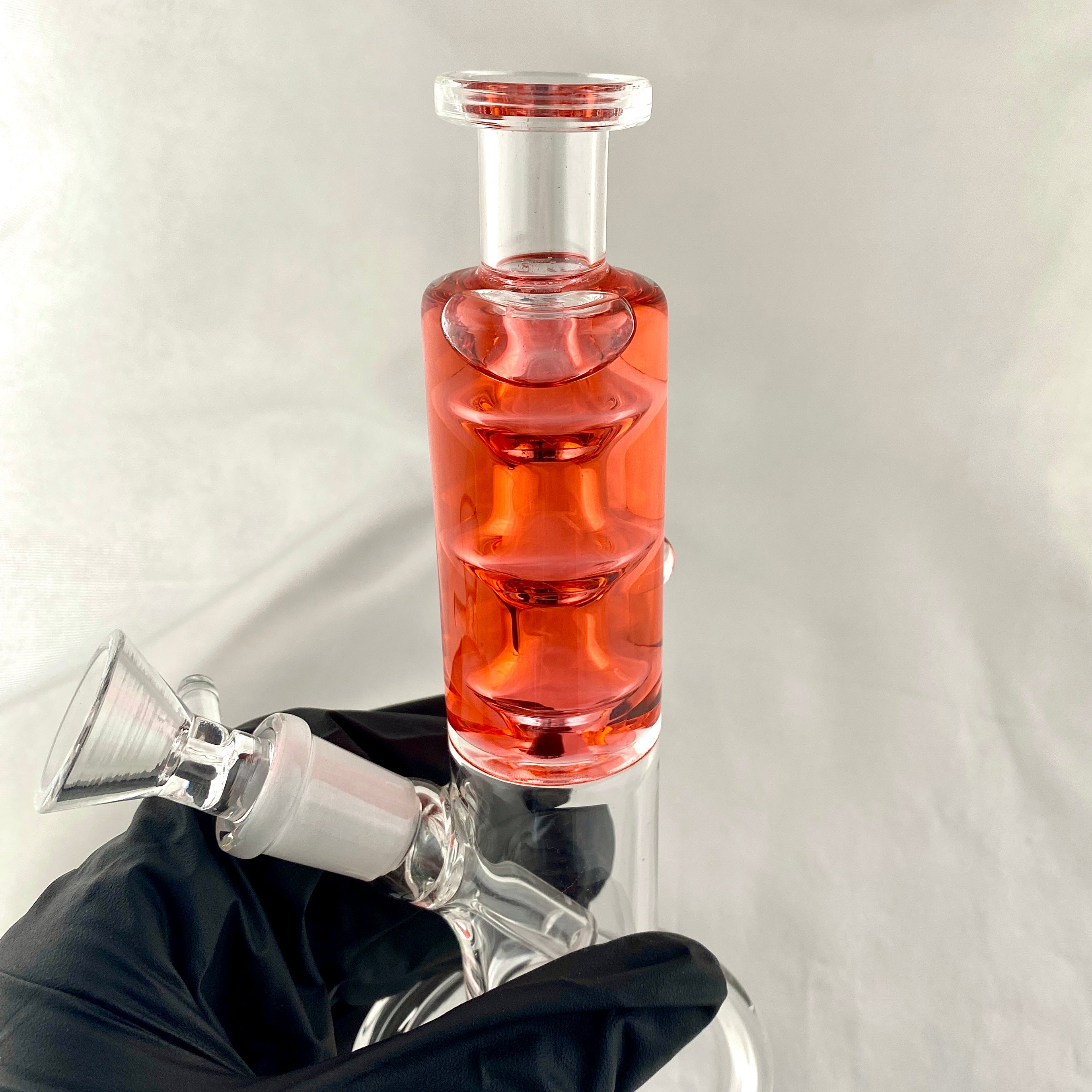 Glass water pipe with red liquid on a white background