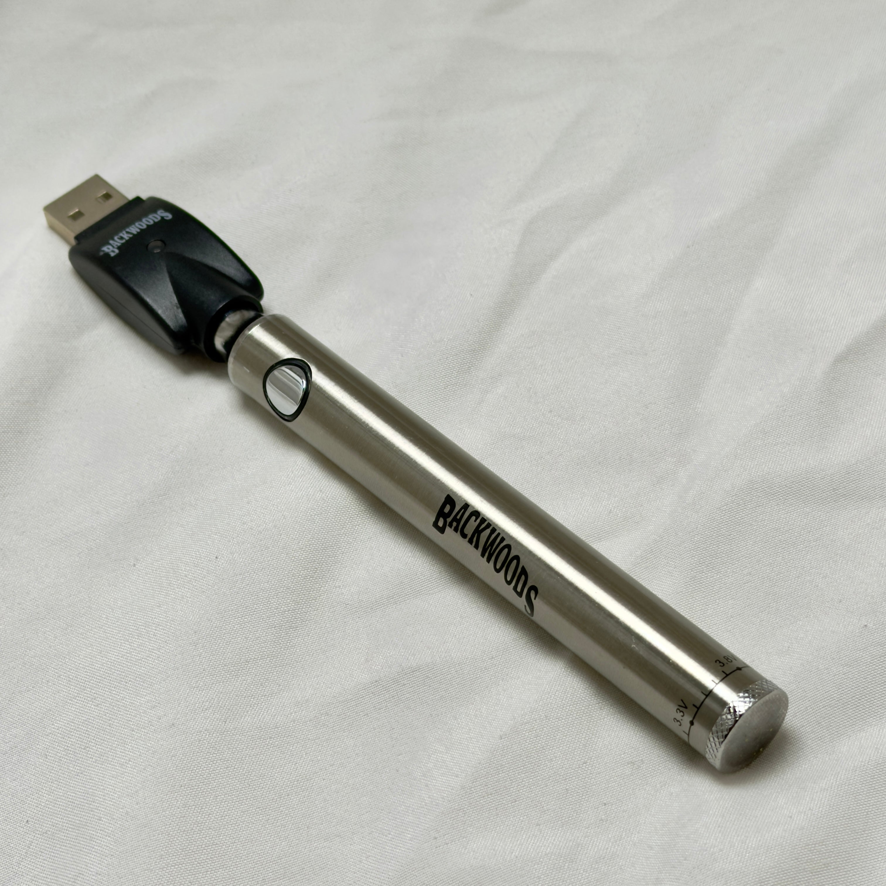 Silver electronic device with USB connector on a white fabric background